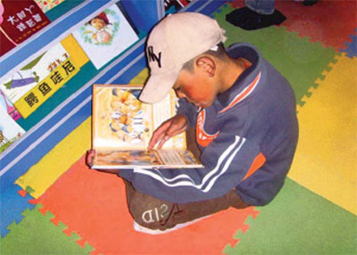 A child reading a book at the language learning resource centre