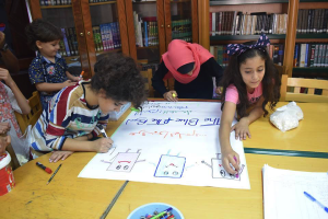 3 children work together at a table to design a poster