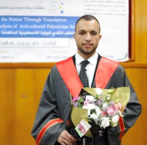 Khalil Abu Yahikya smiles at the camera holding a bunch of flowers and wearing a graduation gown with red trim. over his suit and tie. Behind him is a wood panelled wall with a poster in Arabic. 