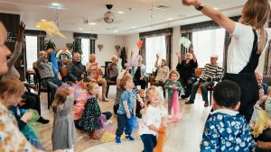 Amanda leads a class of children and older residents in an intergenerational movement and music session.